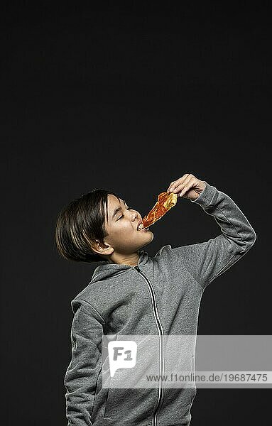 Mittlere Aufnahme Kind ißt Pizza mit Kopierraum