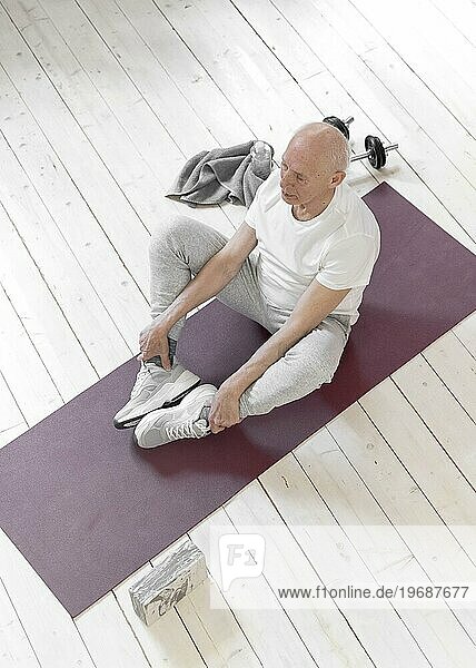 Vollbild Senior Mann sitzend Yogamatte