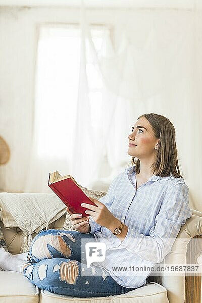 Nachdenkliche Frau liest Buch Sofa