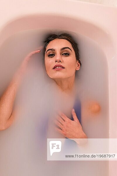 Künstlerisches Porträt der Draufsicht einer schönen Frau in einem Milchbad