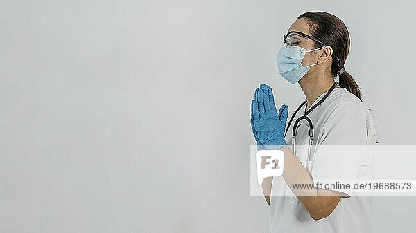 Seitenansicht Ärztin mit medizinischen Maske beten mit Kopie Raum