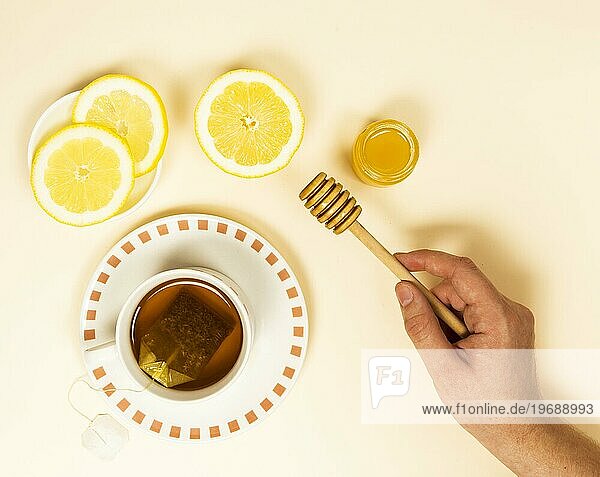 Erhöhte Ansicht menschliche Hand hält Honig Löffel in der Nähe von gesunden Tee Zitrone Scheibe