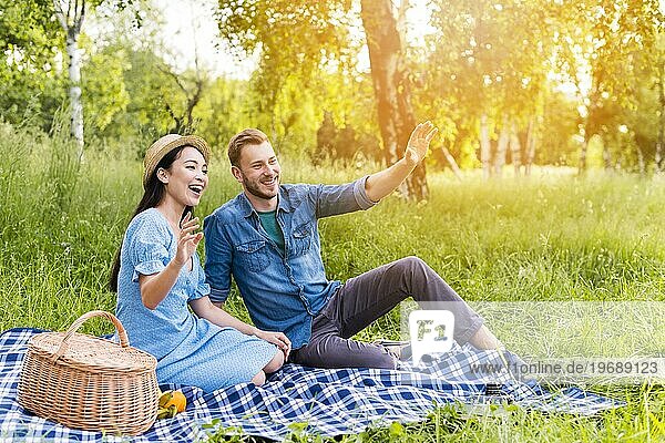 Junges glückliches Paar winkt lächelnd Picknick Natur