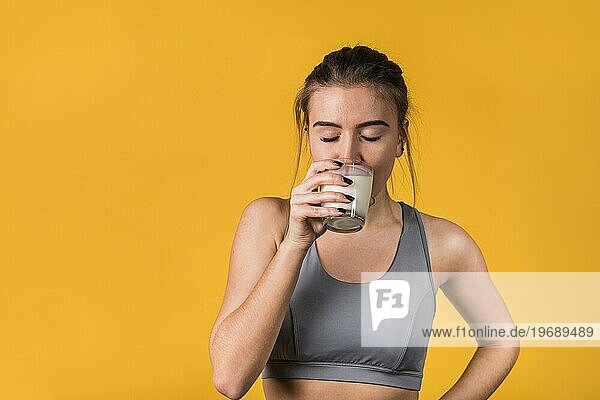 Attraktive junge Frau in Sportkleidung trinkt Milch