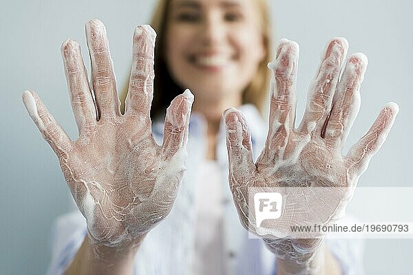 Unscharfe Frau zeigt ihre Hände mit Seife bedeckt