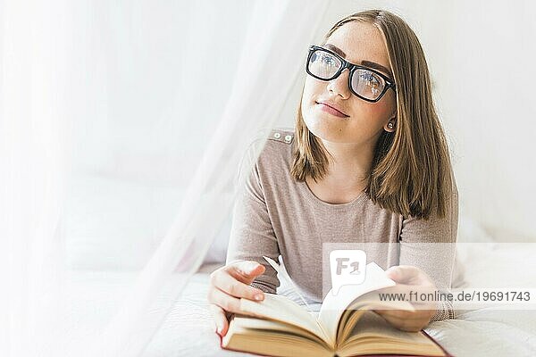 Frau im Bett liegend mit Buch träumend