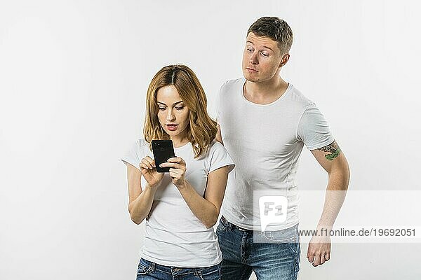 Junger Mann versucht Spionage ihre Freundin s Handy isoliert weißem Hintergrund