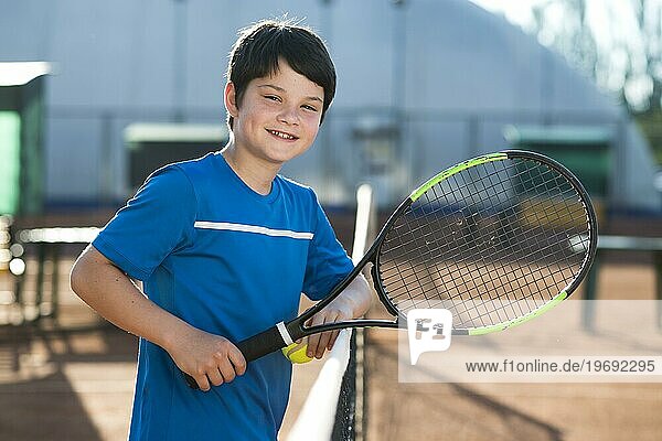 Lächelndes Kind  das sich auf dem Tennisnetz ausruht