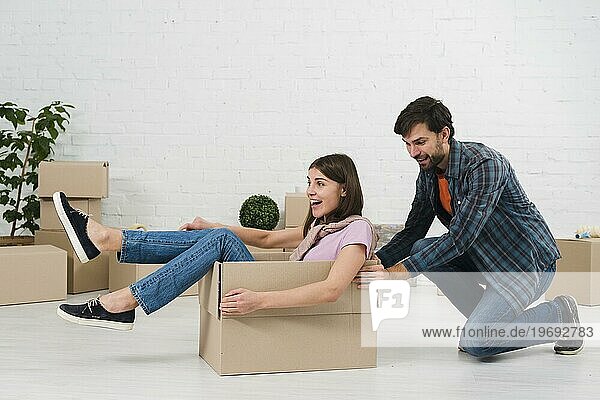 Ehemann schiebt seine Frau sitzend Karton