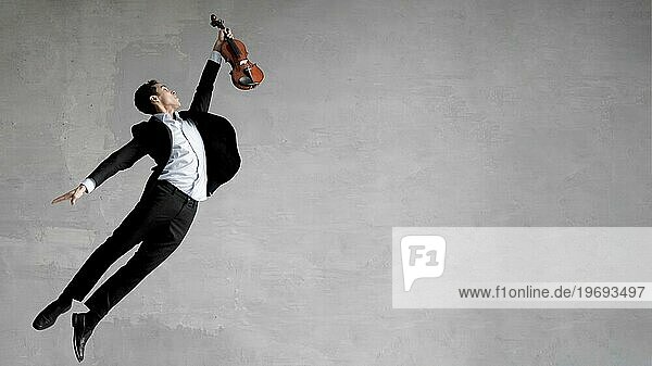 Seitenansicht eines männlichen Musikers  der in der Luft posiert und eine Geige hält