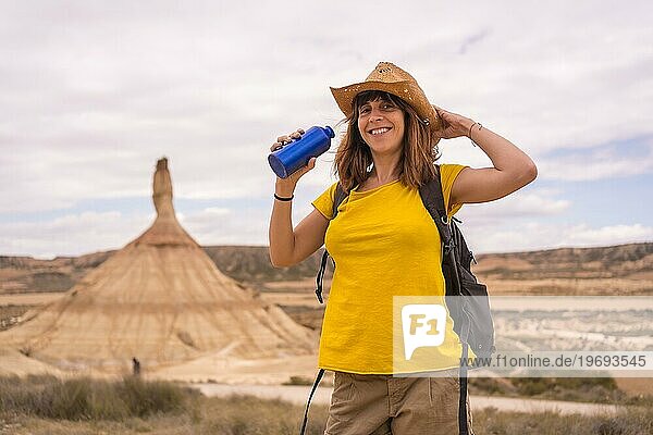 Porträt einer glücklichen  umweltbewussten Frau  die in der Wüste Wasser trinkt