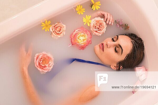 Künstlerisches Porträt von oben eines Modells  das ein Milchbad mit Blumen nimmt