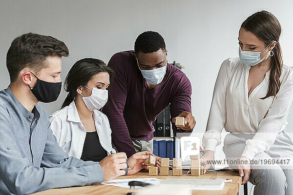 Kollegen  die sich während der Pandemie mit medizinischen Masken im Büro treffen