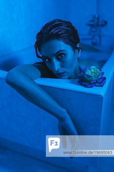 Vertikale künstlerische Porträt mit blauen Lichtern eines sinnlichen entspannte Frau in einer entspannenden Momente in einer heißen Röhre