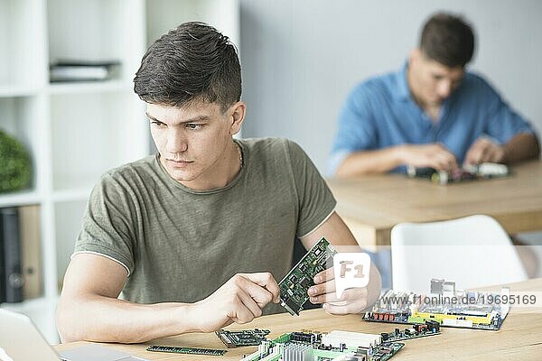 Junger IT Student übt Hardware Ausrüstung an der Werkbank
