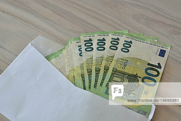 Viele einhundert Euro Scheine in einem Kuvert auf einem Tisch  Symbolbild für Bargeld  Reichtum oder Korruption