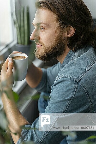 Mann hält Kaffeetasse in Großaufnahme