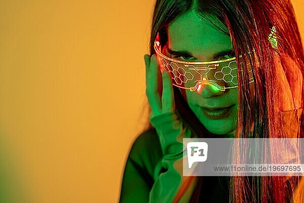 Futuristisches Studioporträt mit Neonlicht des Augenkontakts einer transsexuellen futuristischen Person  die eine intelligente Brille benutzt
