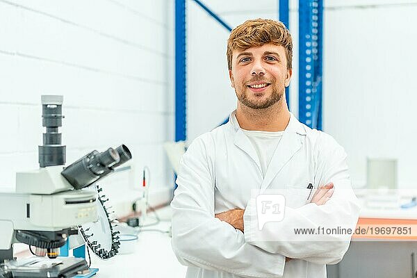 Porträt eines jungen Biologen  der mit verschränkten Armen in einem Labor steht