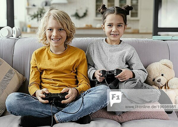 Geschwister auf der Couch mit Joysticks spielen