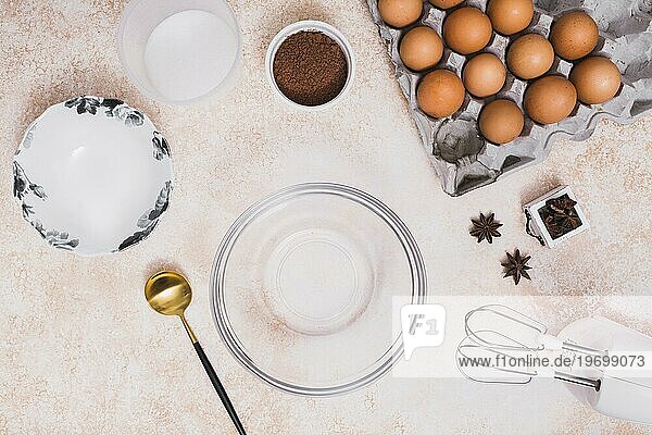 Empty glass bowl plate flour cocoa powder eggs carton star anise electric mixer kitchen counter