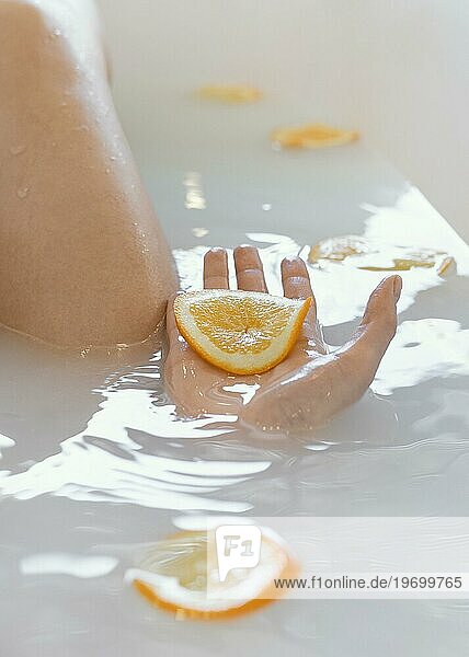 Close up Frau beim Baden mit Orangenscheiben Wasser