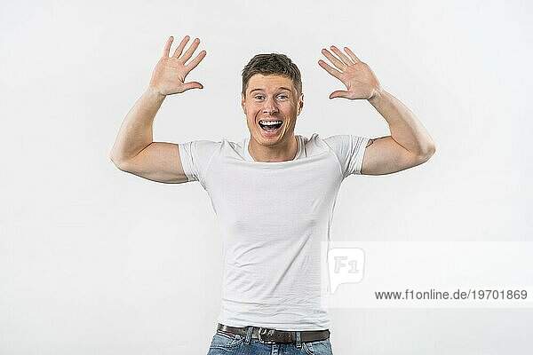 Aufgeregter junger Mann hebt die Arme und gibt High Five vor weißem Hintergrund
