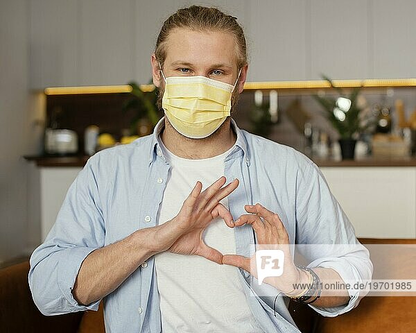 Frontansicht Vater mit medizinischer Maske macht Herzzeichen mit Händen