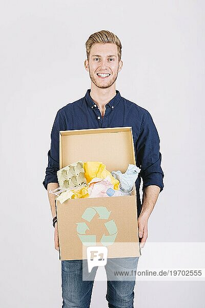 Porträt Mann hält Karton voller Müll mit Recyclingsymbol