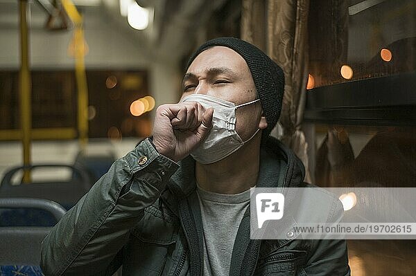 Vorderansicht kranker Mann hustet Bus  während er eine medizinische Maske trägt