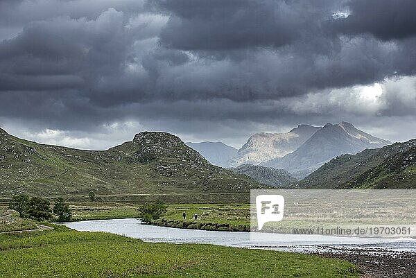 Zwei Wanderer auf einem Weg entlang eines Flusses und sich bildende Regenwolken in Wester Roß  Schottische Highlands  Schottland  UK