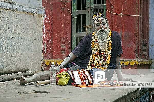Ein behinderter Sadhu verkauft Opfergaben für einen Tempel in Varanasi  Uttar Pradesh  Indien  Asien