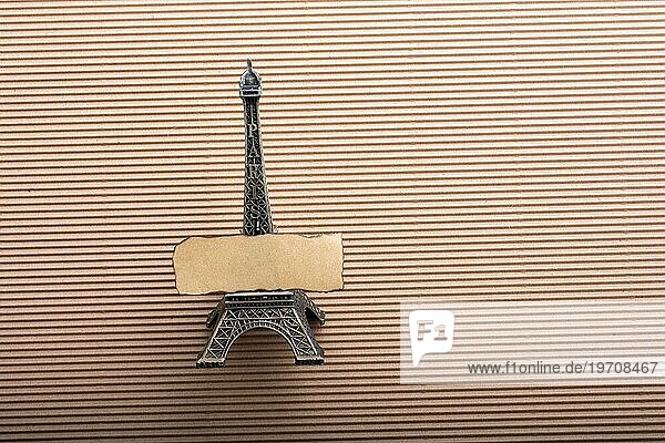 Verbranntes Stück Papier auf Modell Eiffelturm auf Karton