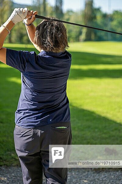 Weibliche Golferin macht einen Golfschwung an einem sonnigen Tag in der Schweiz