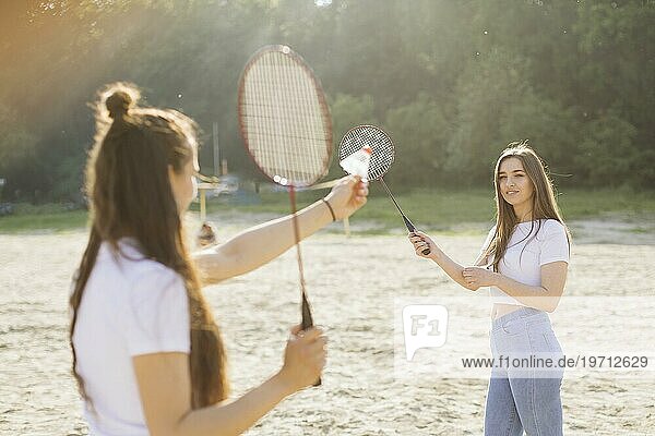 Mittlere Einstellung glückliche Mädchen spielen Badminton