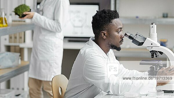 Seitenansicht eines männlichen Forschers im Labor mit Mikroskop