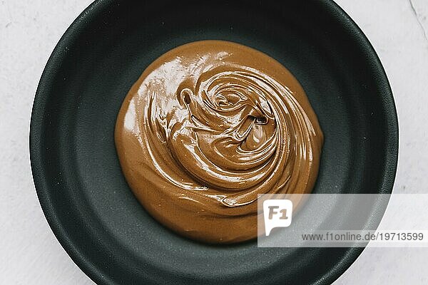 Leckere geschmolzene Schokolade schwarze Schale weißer Hintergrund