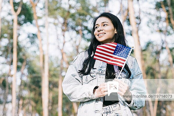 Hispanisches Teenagermädchen das einen Stock mit amerikanischer Flagge hält
