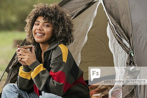 Lächelnde Frau beim Camping im Freien mit Zelt
