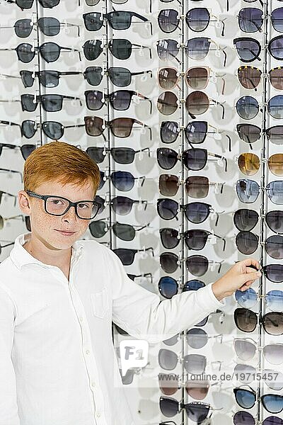 Junge wählt eine Brille aus und sucht eine Kamera Optik