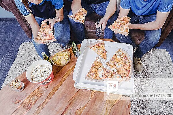 Freunde essen Pizza und schauen Fußball