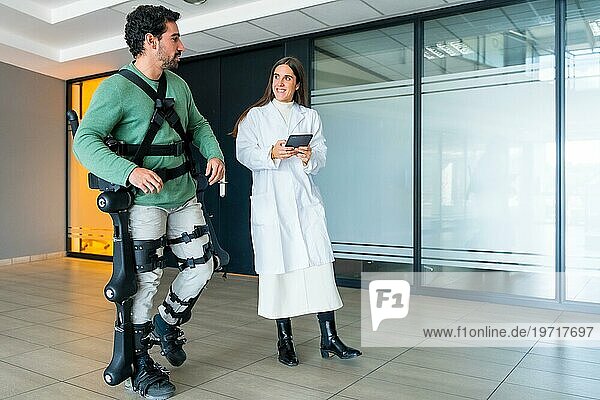 Mechanisches Exoskelett  Ärztin  Physiotherapeutin  die mit einer behinderten Person mit Hilfe eines Roboterskeletts geht  Physiotherapie in einem modernen Krankenhaus  futuristische Physiotherapie