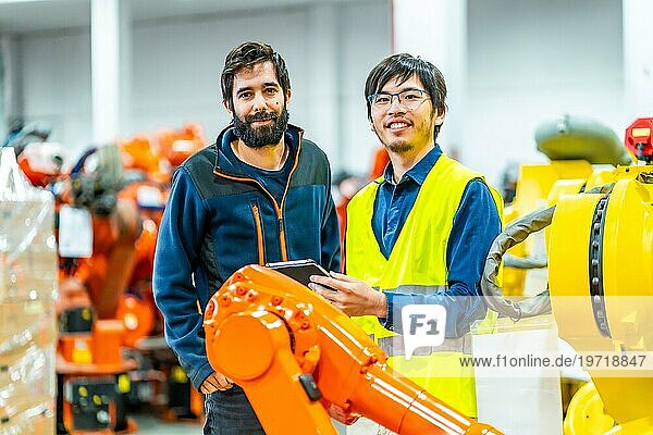 Porträt zweier junger multiethnischer Ingenieure in der Industrieroboterbranche  die in die Kamera schauen und lächeln