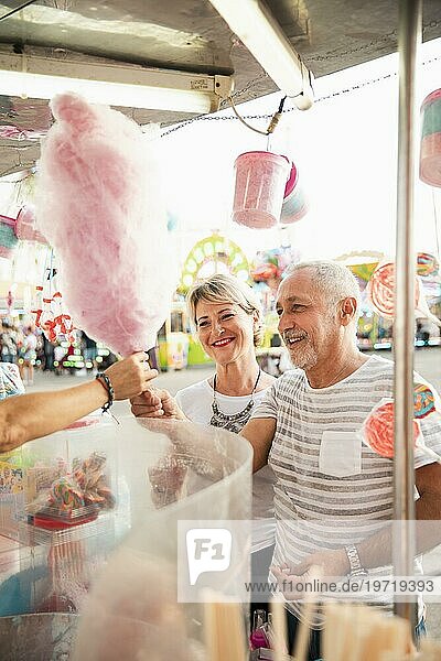 Hochformatiges glückliches Paar beim Kauf von Zuckerwatte