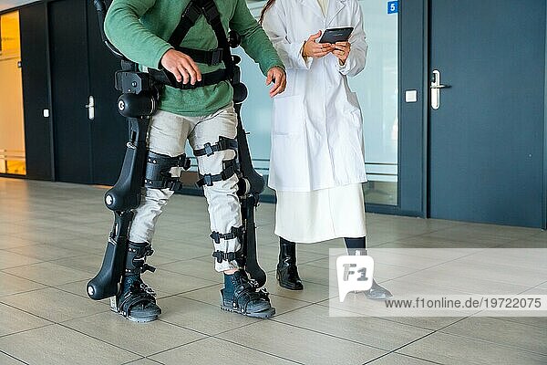 Mechanisches Exoskelett  Ärztin  Physiotherapeutin mit unkenntlicher behinderter Person mit Roboterskelett in der Rehabilitation  Physiotherapie in einem modernen Krankenhaus  futuristische Physiotherapie