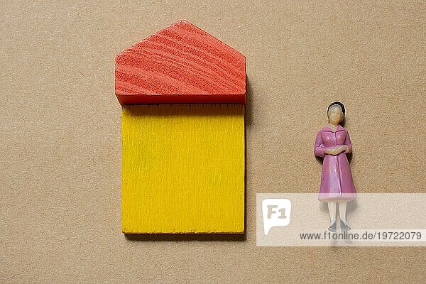 Frauenfigur von House aus Holzklötzen als Konzept von Kauf  Verkauf  Vermietung von Immobilien  Bau und Öko Stil