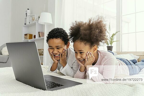 Zwei Geschwister spielen zu Hause zusammen Laptop