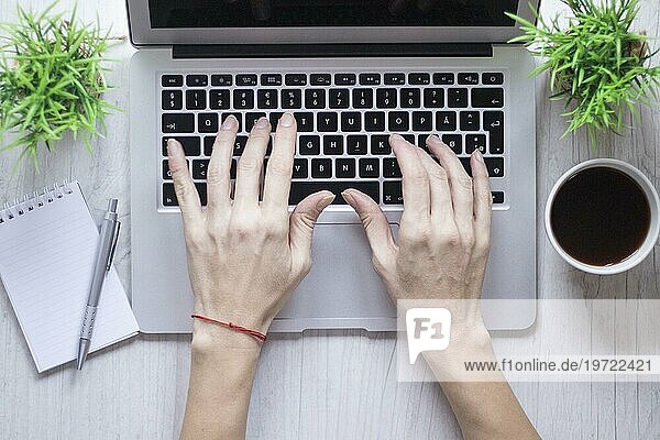 Crop Hand mit Laptop in der Nähe von Kaffee Notebook
