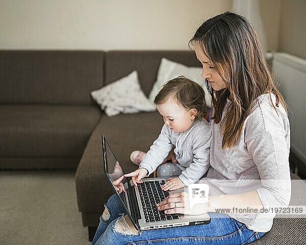 Seitenansicht Mutter mit ihrem Kind auf dem Sofa sitzend mit Laptop