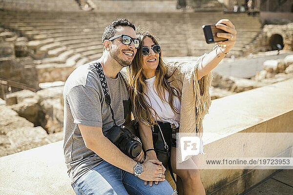 Touristisches Paar sitzt zusammen und macht ein Selfie mit dem Handy